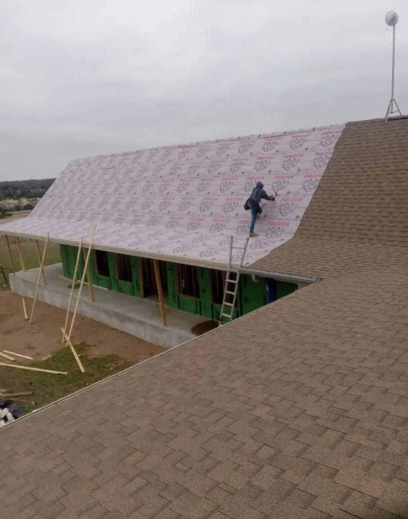 Worker preparing underlayment for a metal roof installation in West Carson